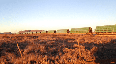 Low-down view of a grassy field with piles of pipeline pieces waiting to be constructed